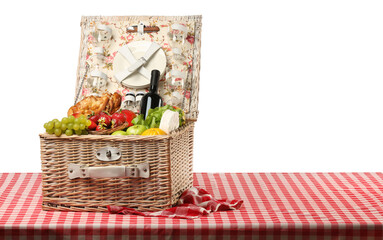 Picnic wicker basket with food, tableware and bottle of wine on table against white background. Space for text