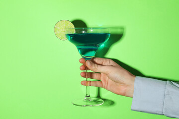Woman with glass of refreshing cocktail on green background, closeup