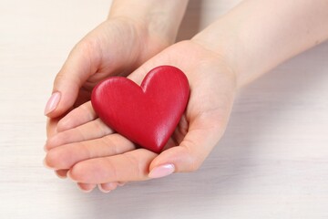 Woman with red decorative heart at white wooden table, closeup