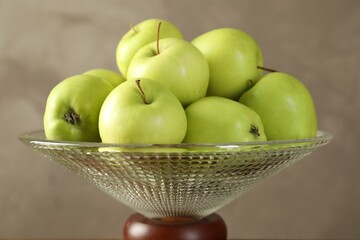 Glass vase with fresh green apples on gray background, closeup