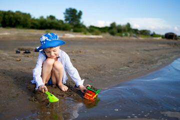 A young child is joyfully enjoying a beautiful sunny day at the beach while playing with colorful toys along the water