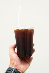Ice black coffee takeaway plastic glass on man hand