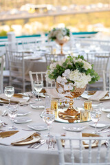 Minimalist wedding table setting with white linens, gold accents, and greenery, perfect for a modern outdoor wedding