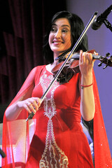Young beautiful violinist in a red dress plays the violin