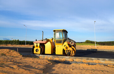 Obraz premium Asphalting paving repairing works. Vibrator compactor machine on roadworks on city street. Asphalt road roller on road construction. Road Construction Equipment. Vibration roller on Asphalting.