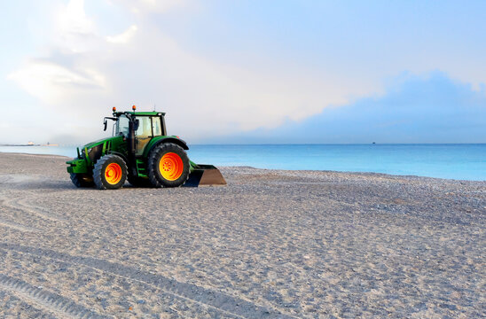 Clining beach and maintenance. Tractor grooming sand on beach shore in Almarda, Spain. Getting beach ready for summer vacation season. Beach grooming machinery.