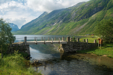 Summer landscape with an old stone bridge across the small river in rural Norway.