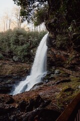 Vertical shot of the scenic Dry Falls cascading down a rocky cliff at sunset in North Carolina, USA