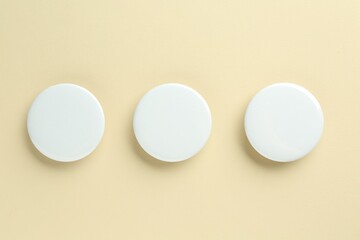 White button badges on beige background, flat lay. Mockup for design