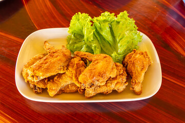 A plate of fresh, hot, crispy fried chicken on a white plate and wooden table.