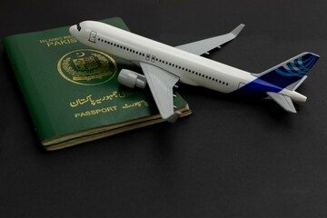 Pakistani Passport with Airplane Model on Black Background