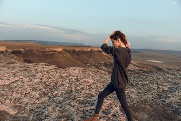 Golden hour triumph woman standing on mountain peak at sunset with hands on head