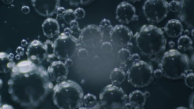 Extreme no people macro of drop of saliva with air bubbles being rotated on specimen table under microscope in laboratory in clockwise motion, on black background