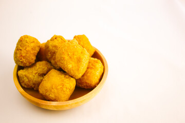 Tahu goreng cripsy, or crispy fried tofu, is one type of snack in Indonesia on wood plate isolated on white background. Perfect for recipe, article, catalogue, commercial, or any cooking contents
