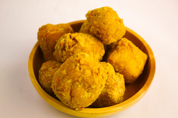 Tahu goreng cripsy, or crispy fried tofu, is one type of snack in Indonesia on wood plate isolated on white background. Perfect for recipe, article, catalogue, commercial, or any cooking contents

