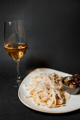 Delicious pasta with cheese and fragrant herbs, accompanied by a beautiful glass of white wine in a cozy and nice restaurant