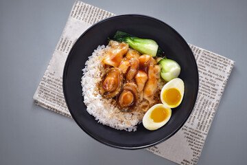 Abalone fish maw with rice with boiled egg and pickled vegetables served in bowl isolated on napkin top view of chinese food on grey background