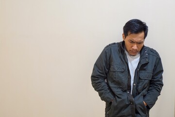 Portrait of A Southeast Asian man wearing a jacket and grimacing because he is very cold, trying to get warm.