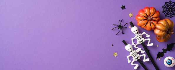 Flat lay of playful Halloween decorations including pumpkins, skeletons, and spooky elements on a purple background