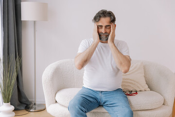 Home, senior man and headache on sofa for stress, emotional conflict and temporal vertigo. Living...