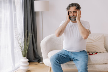 Home, senior man and headache on sofa for stress, emotional conflict and temporal vertigo. Living...