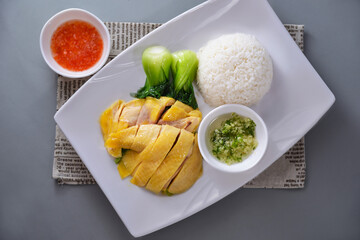 Hainan Chicken Rice with pickled vegetables and sauce served in dish isolated on napkin top view of chinese food on grey background