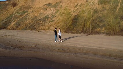 Young couple in love walking on the beach and spinning holding hands. Aerial view of the beach. 4k