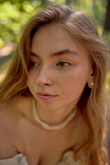 beautiful teenage girl in a silk skirt and a corset in the old money style walks in the park and along the river bank