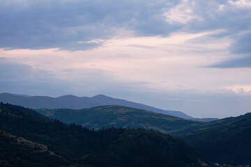Gently pink sunset with the setting sun behind the mountains.