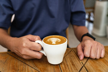 Man holding a cup of coffee latte at cafetaria
