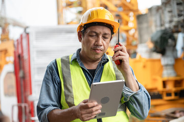 Obraz premium Portrait Asia engineer man worker use notebook computer with spare crane background 