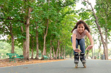 Happy girl going on her in-line skates at public park, health care and active weekends