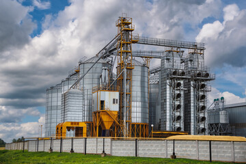 modern granary elevator with silver silos on agro-processing and manufacturing plant for processing drying cleaning and storage of agricultural products, flour, cereals and grain.