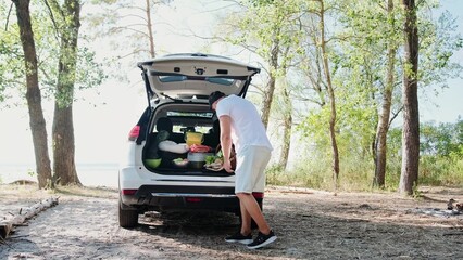 Happy young couple arriving for a picnic by car near the sea