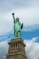 New York, NY, USA - August 4, 2023: Miss Liberty statue from frontal right, against white cloud