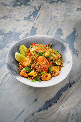 Stir-Fried spicy red parboiled rice with king prawns, seafood and vegetable served as close-up in an Asia style bowl