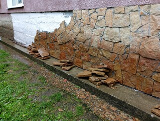 Sandstone stones are stacked near the wall of the house for its installation on the concrete...