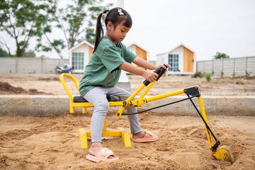 Children playing with toy excavator construction machinery in sand pool