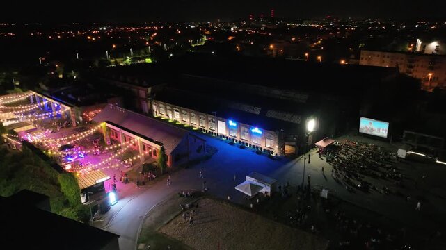 Aerial drone view of summer evening outdoor cinema in the city. The colorful heart of night meetings in the center of a medium-sized city. Night party zone in the city center. Dabrowa Gornicza, Poland