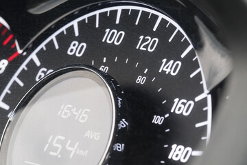 Close-up of car speedometer with digital display showing average speed and time