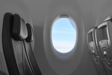 Comfortable black seats and window on the plane with a view of blue sky