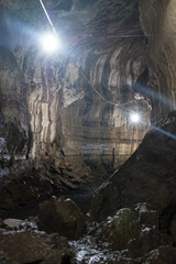 Deep, illuminated natural cave with rough rock formations and a dimly lit path