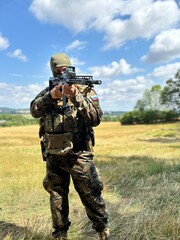 Fototapeta premium A Russian soldier guards the captured area. A soldier in camouflage with a rifle in his hand. Tracks enemy movement.