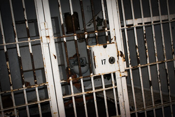 old prison bars showing a prison cell locked with bed and toilet.