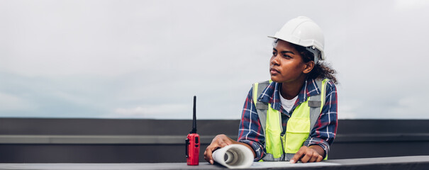 Team Engineers with draft plan of building on constructing site.