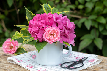 Blumenstrauß mit pink Rose und Hortensien-Blüten in rustikaler Emaille-Tasse	