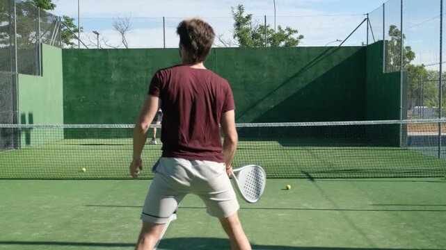 Two men playing tennis on an outdoor court, hitting forehand and backhand shots under a clear sky