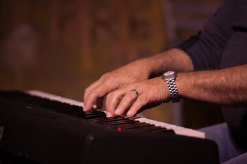 Close-up of a musician's hands playing a keyboard, highlighting the intricate movements and focus. The background is artistically blurred.
