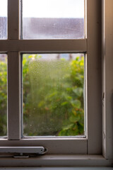 Wooden frame double glazed window showing condensation droplets between two panes of glass...