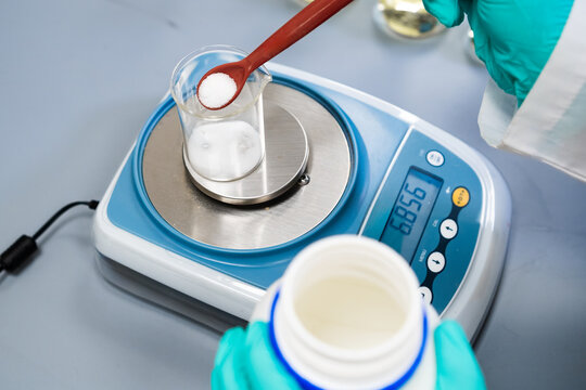 A woman utilizes laboratory balances to measure powder samples.